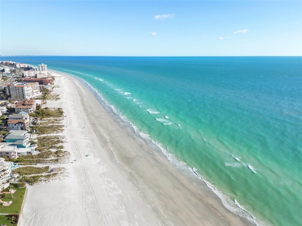 An aerial view shows a sandy beach bordering turquoise ocean water next to coastal buildings — 17920 GULF BOULEVARD UNIT 208, REDINGTON SHORES, FL