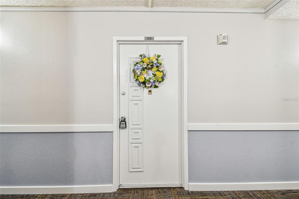 A white apartment door with a floral wreath is centered on a two-toned wall — 17920 GULF BOULEVARD UNIT 208, REDINGTON SHORES, FL