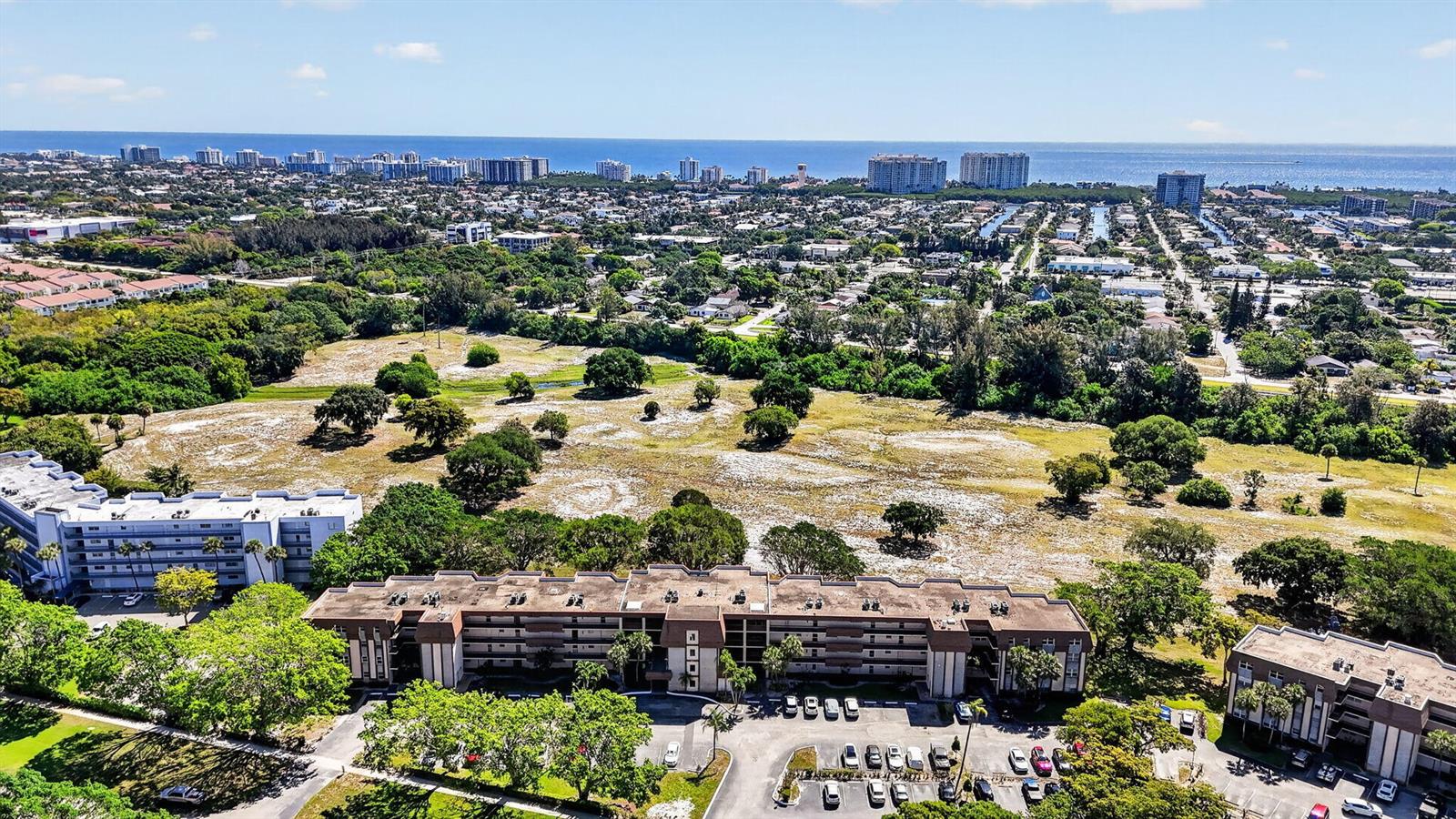 Aerial view of multi-story apartment buildings situated next to a large, open grassy field — 6300 NW 2nd Avenue # 306, Boca Raton FL 33487, BOCA RATON, FL