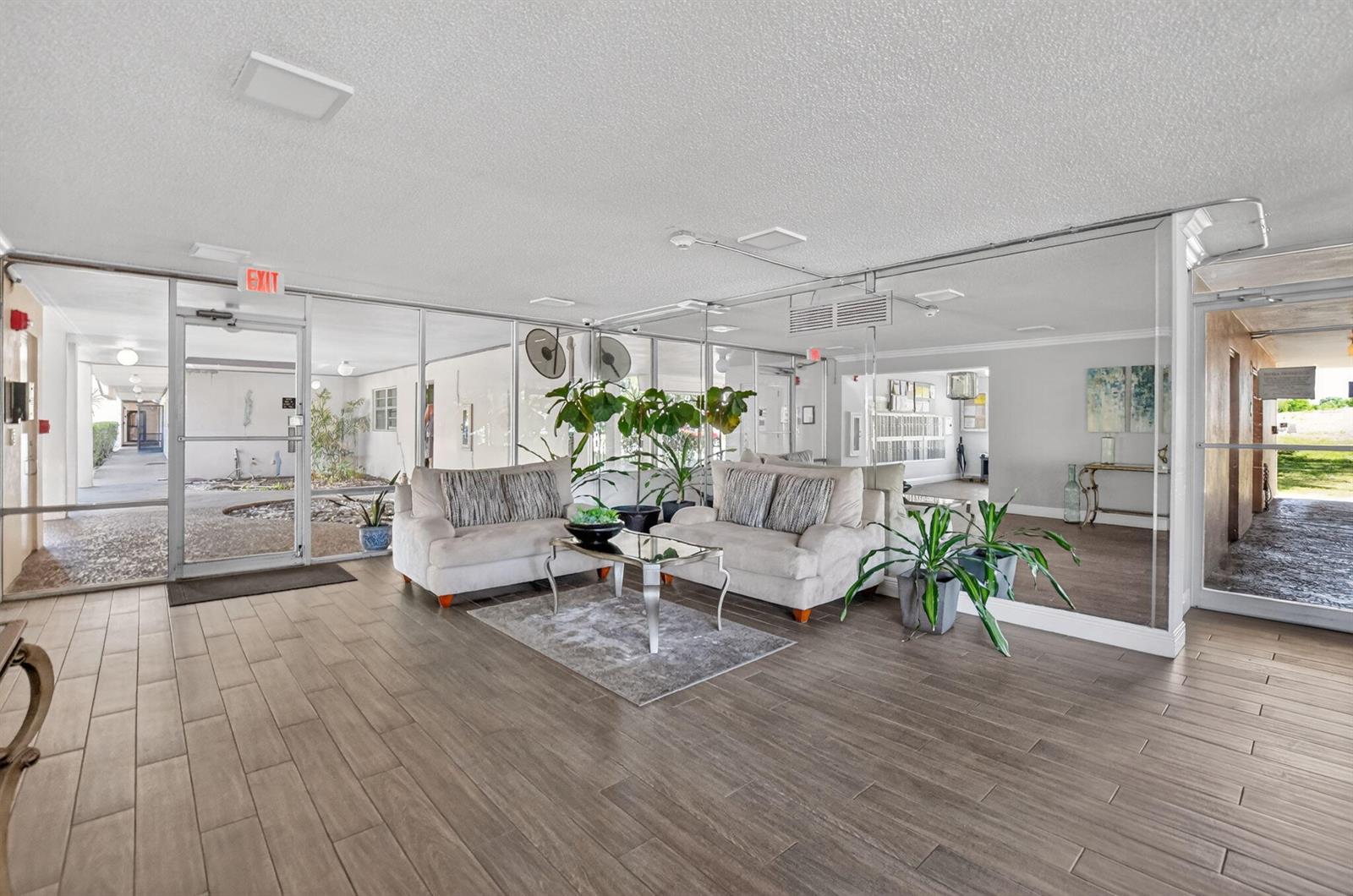 A lobby features two sofas, a glass coffee table, tile flooring, and mirrored walls — 6300 NW 2nd Avenue # 306, Boca Raton FL 33487, BOCA RATON, FL