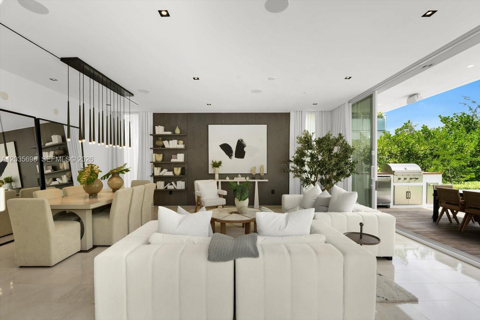 A modern open-plan living and dining area features white furniture, dark wood paneling, and a patio — 810 W 47 CT, Miami Beach FL 33140, MIAMI BEACH, FL