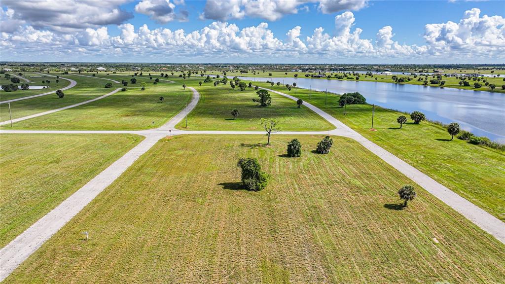 An aerial view shows a vacant, grassy residential lot next to a lake and road — 5 WILLOW ROAD, PLACIDA, FL
