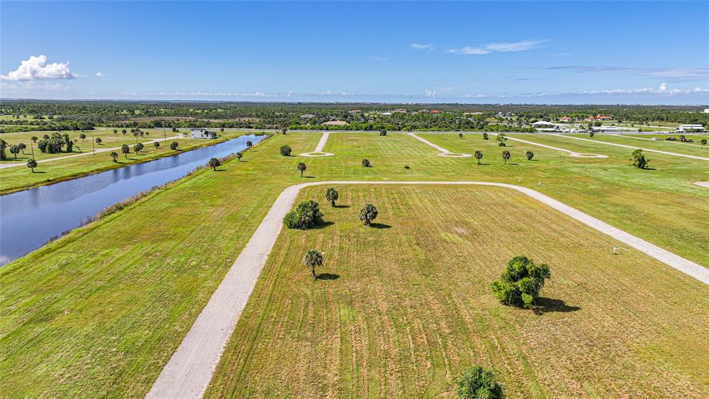 An aerial view shows a large, undeveloped grassy lot with a canal and paved roads — 5 WILLOW ROAD, PLACIDA, FL
