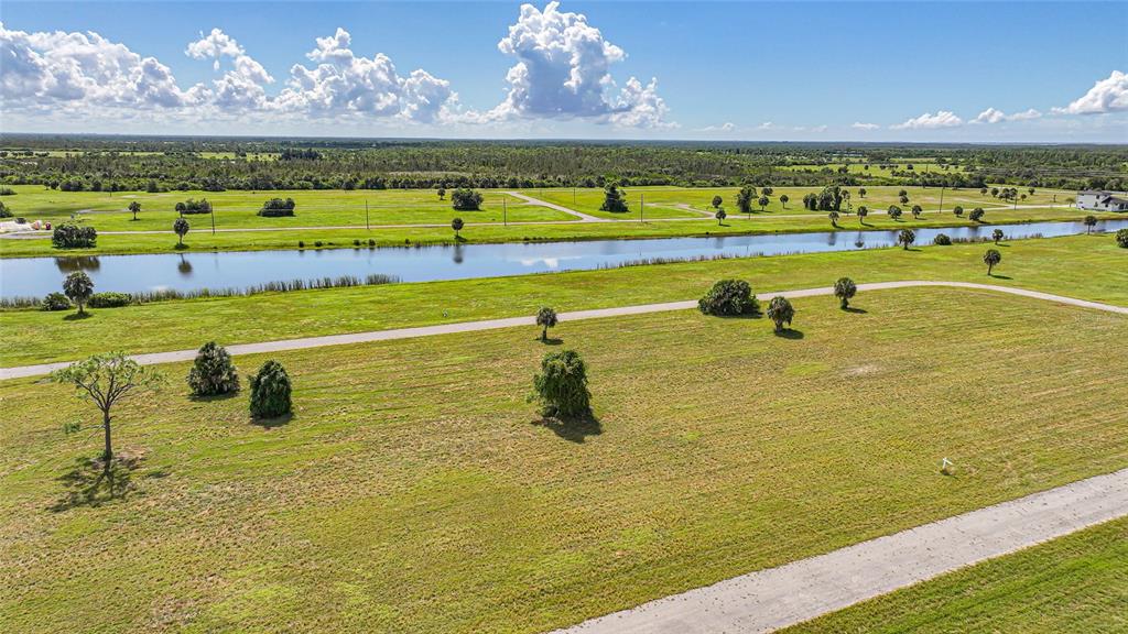 An aerial view shows a vacant grassy lot with scattered trees and a nearby canal — 5 WILLOW ROAD, PLACIDA, FL