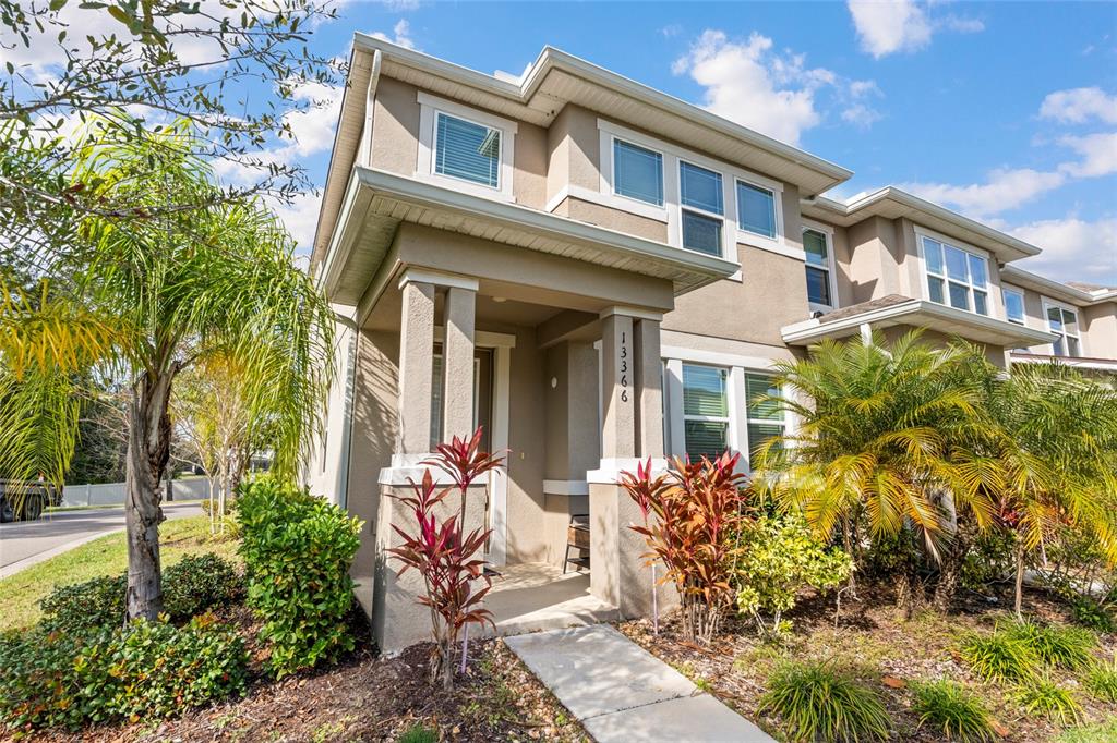 A two-story townhouse exterior features a covered entryway, beige stucco siding, and landscaped front yard — 13366 ABUELA ALLEY, WINDERMERE, FL