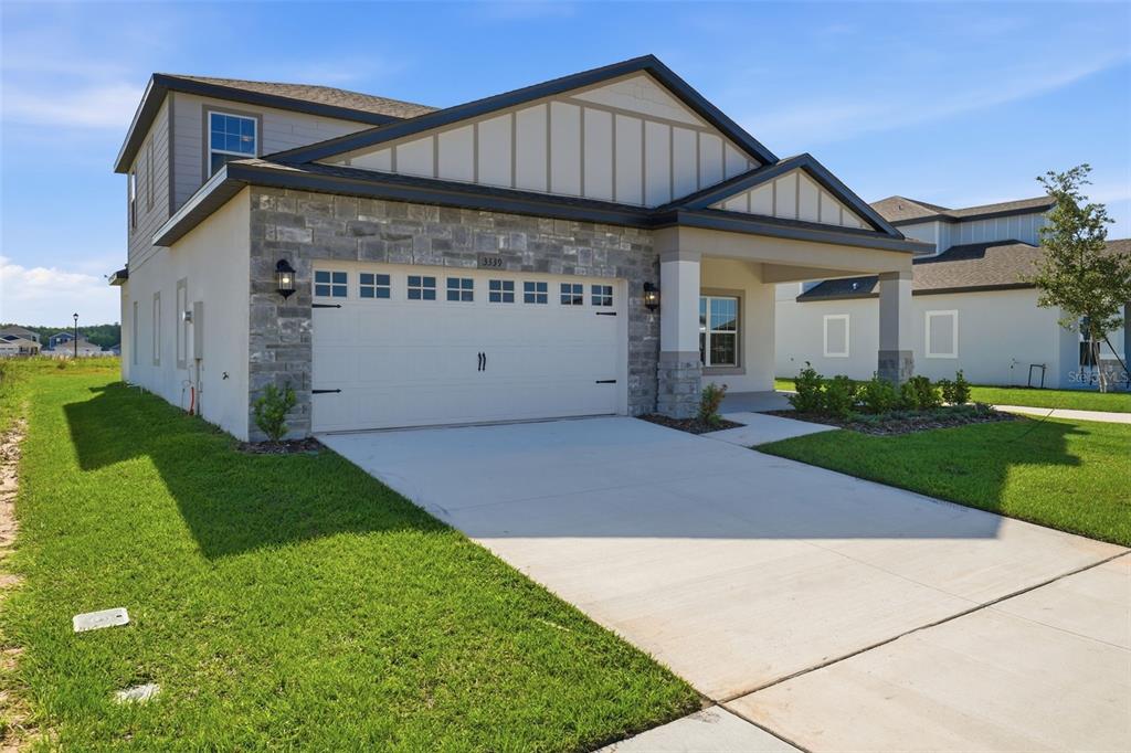 A two-story house with a stone-accented facade, a two-car garage, and a covered front porch — 3339 CHINOTTO DRIVE, LAKE ALFRED, FL
