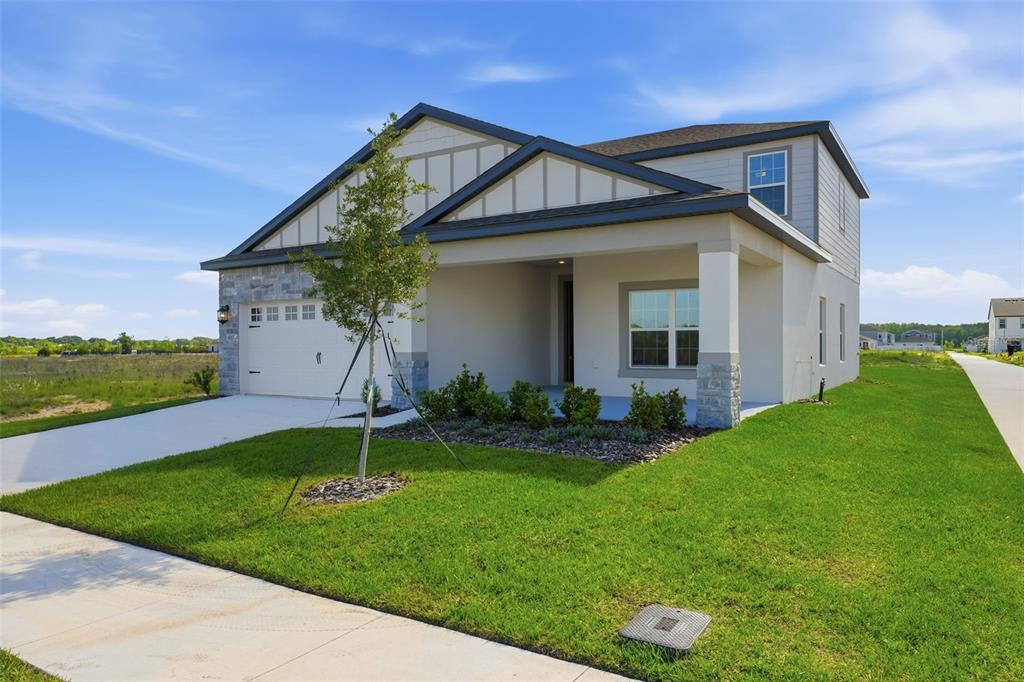 A two-story suburban house with a stone-accented facade, a front porch, and a concrete driveway — 3339 CHINOTTO DRIVE, LAKE ALFRED, FL