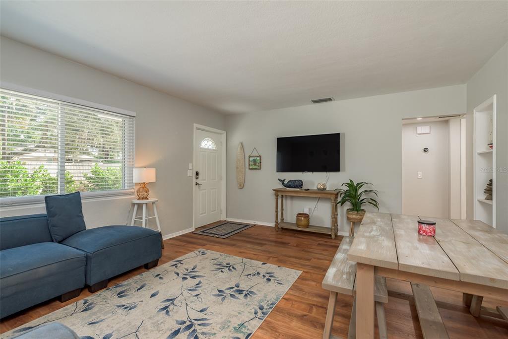A living and dining area features wood-look flooring, a blue sofa, and a wall-mounted television — 1253 UNION STREET, CLEARWATER, FL