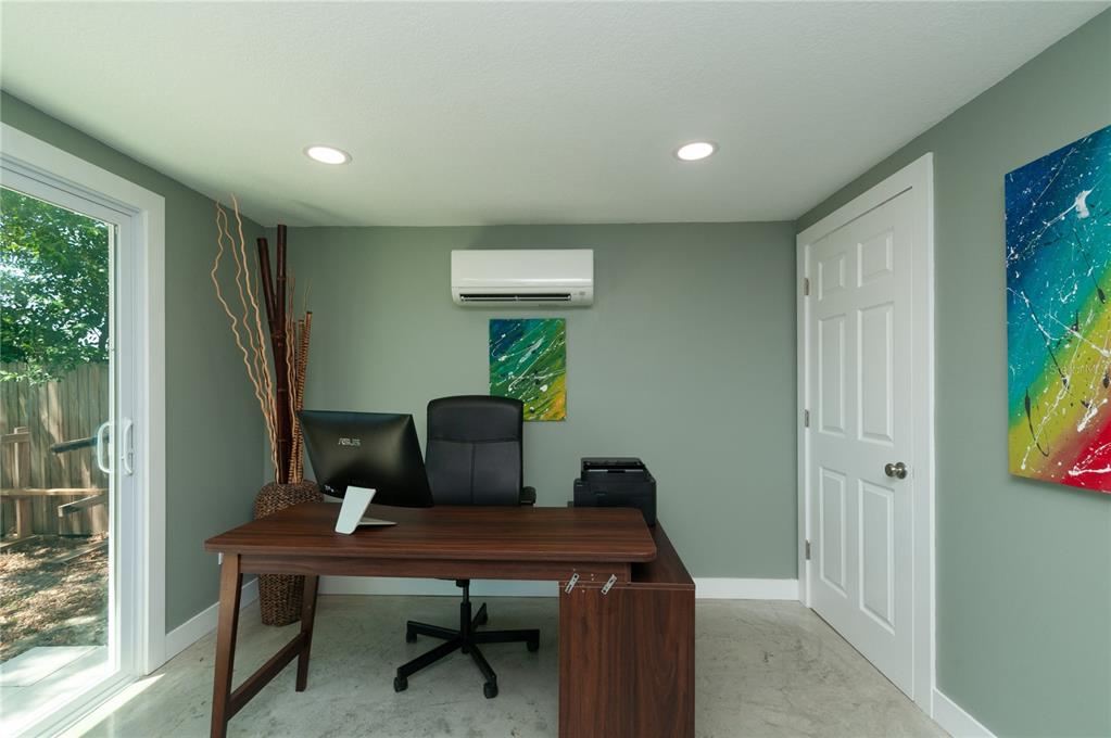 A home office with a wooden desk, black chair, wall-mounted air conditioner, and sliding glass door — 1253 UNION STREET, CLEARWATER, FL