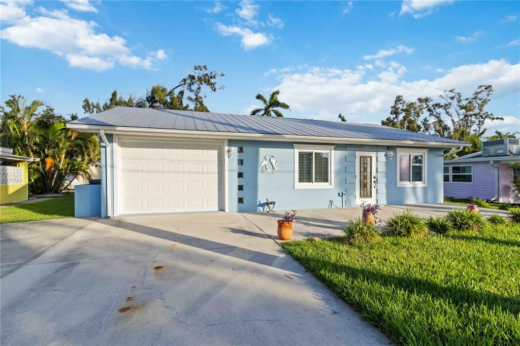 A light blue single-story house with a metal roof, a garage, and a concrete driveway — 4603 103RD STREET W, BRADENTON, FL