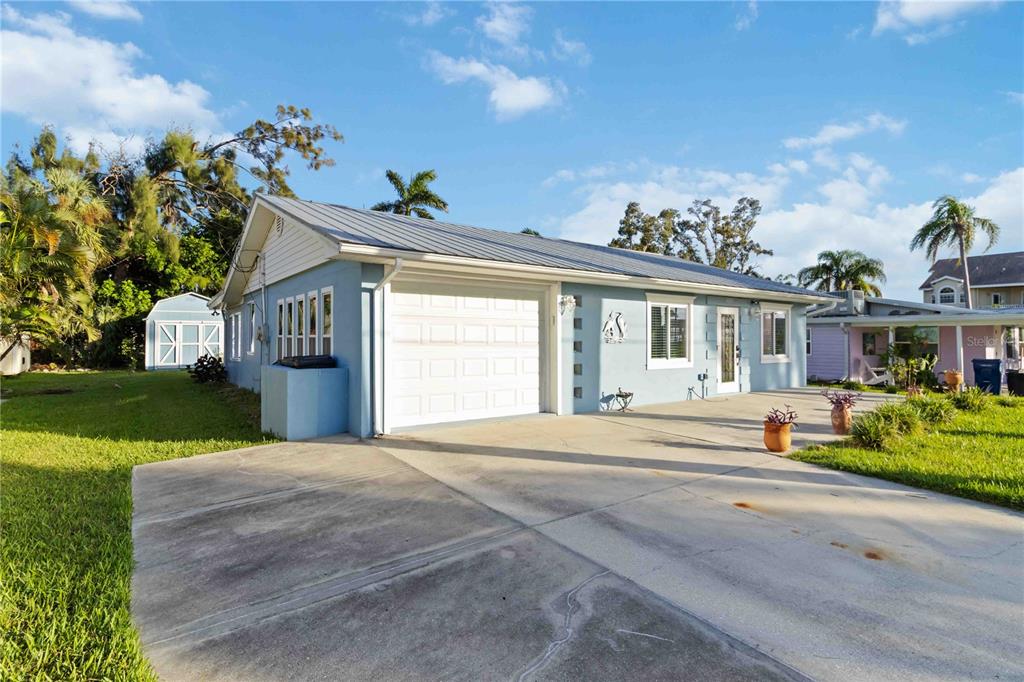 A light blue single-story house with a metal roof, garage, and concrete driveway — 4603 103RD STREET W, BRADENTON, FL