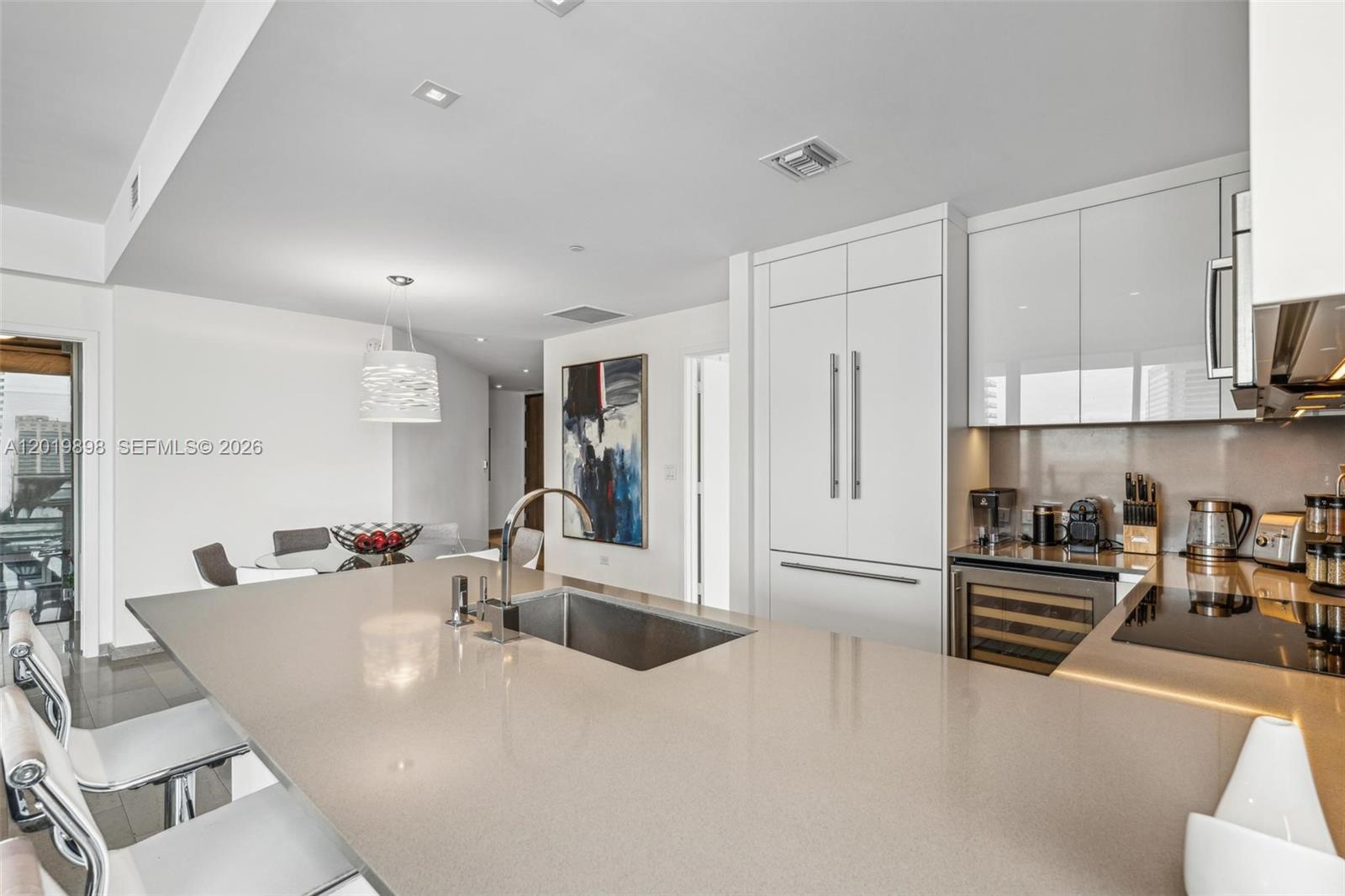 A modern kitchen features a large island with a sink, white cabinetry, and stainless appliances — 88 SW 7th St # 2111, Miami FL 33130, MIAMI, FL