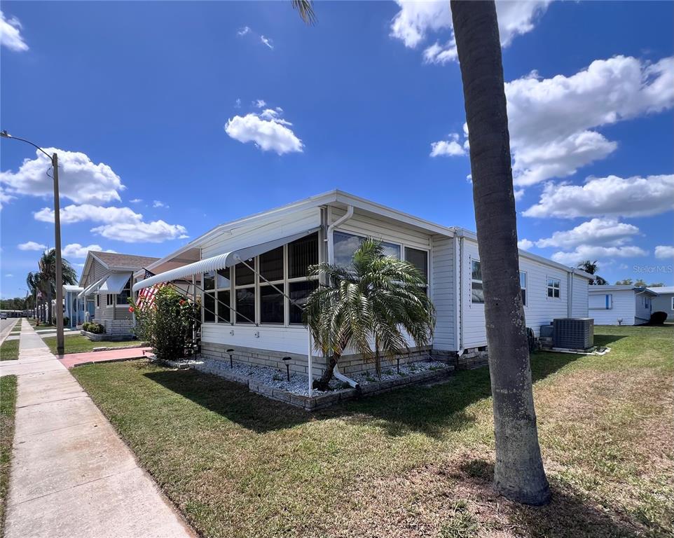 A white mobile home with a screened-in porch and a palm tree in the yard — 1100 BELCHER ROAD S UNIT 260, LARGO, FL