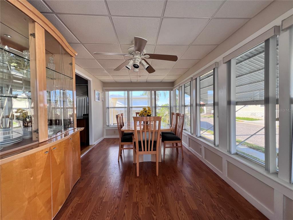 A dining room features wood flooring, a ceiling fan, and large windows overlooking a street — 1100 BELCHER ROAD S UNIT 260, LARGO, FL