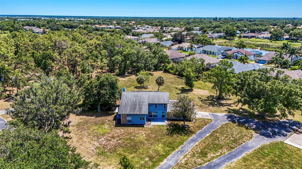 An aerial view shows a blue two-story house surrounded by trees and a large yard — 5650 CHURCHILL DOWNS ROAD, SARASOTA, FL