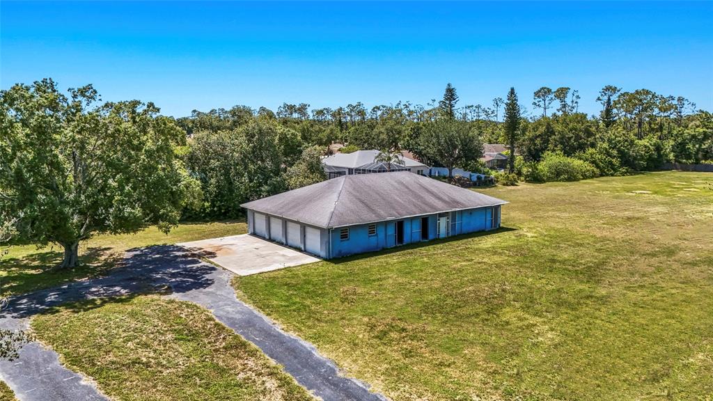 An aerial view shows a blue, single-story building with a multi-car garage and large yard — 5650 CHURCHILL DOWNS ROAD, SARASOTA, FL