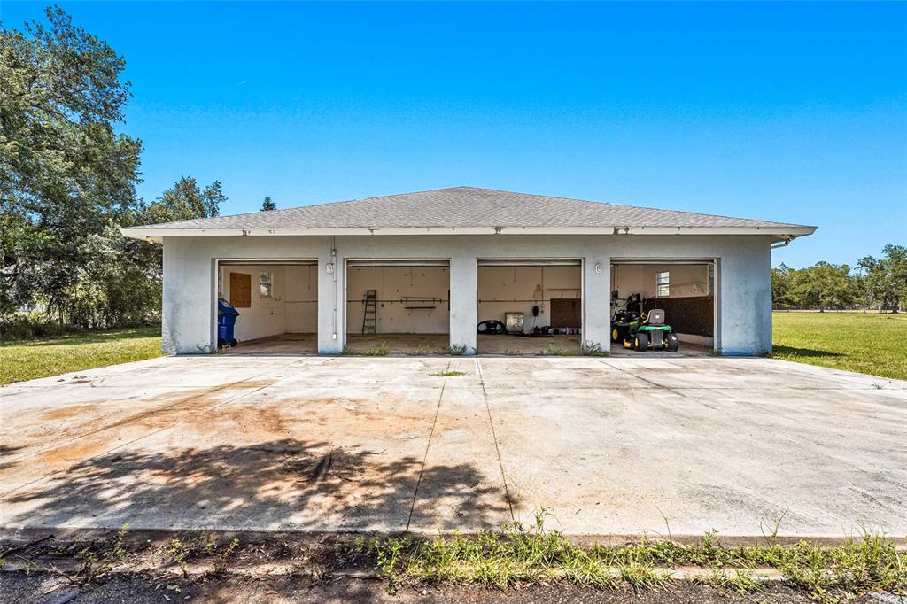 A detached four-car garage with a concrete driveway sits on a grassy lot — 5650 CHURCHILL DOWNS ROAD, SARASOTA, FL