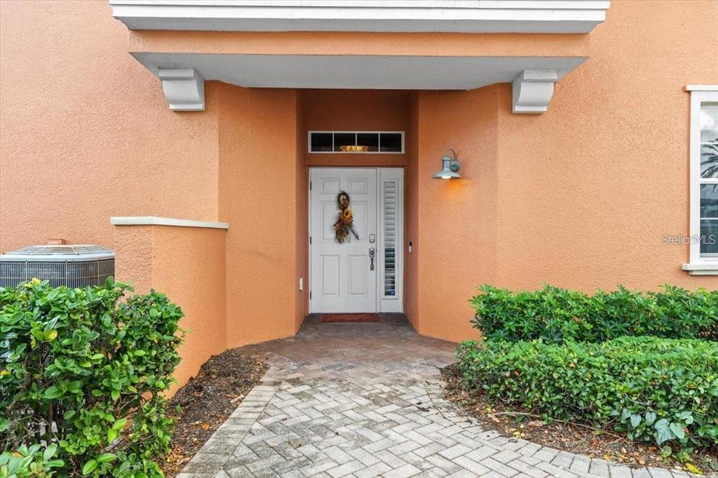 The exterior view shows a peach-colored house with a white front door and paved walkway — 1143 RIVERSCAPE STREET UNIT A, BRADENTON, FL