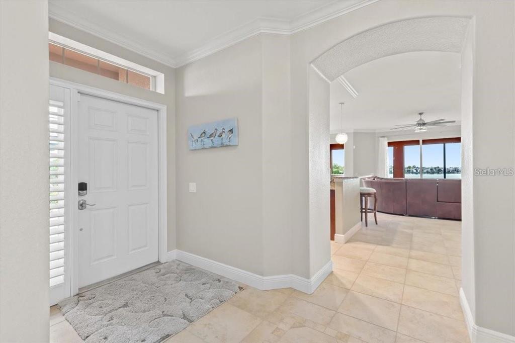 An entryway with a white door, tile flooring, and an arched opening to a living area — 1143 RIVERSCAPE STREET UNIT A, BRADENTON, FL