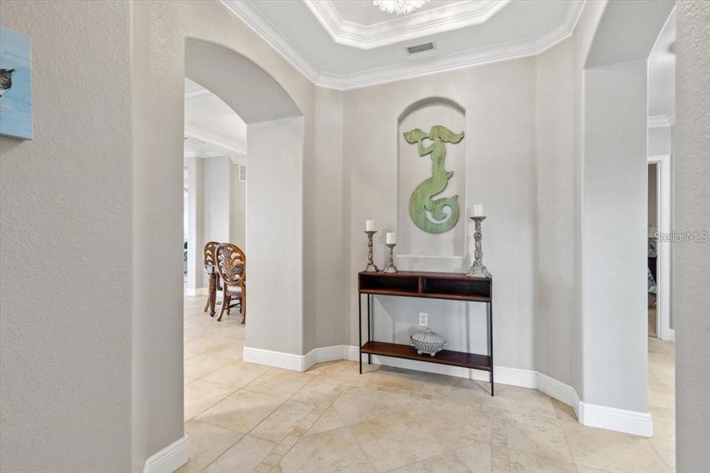 A tiled foyer features an arched wall niche with a decorative sculpture above a console table — 1143 RIVERSCAPE STREET UNIT A, BRADENTON, FL