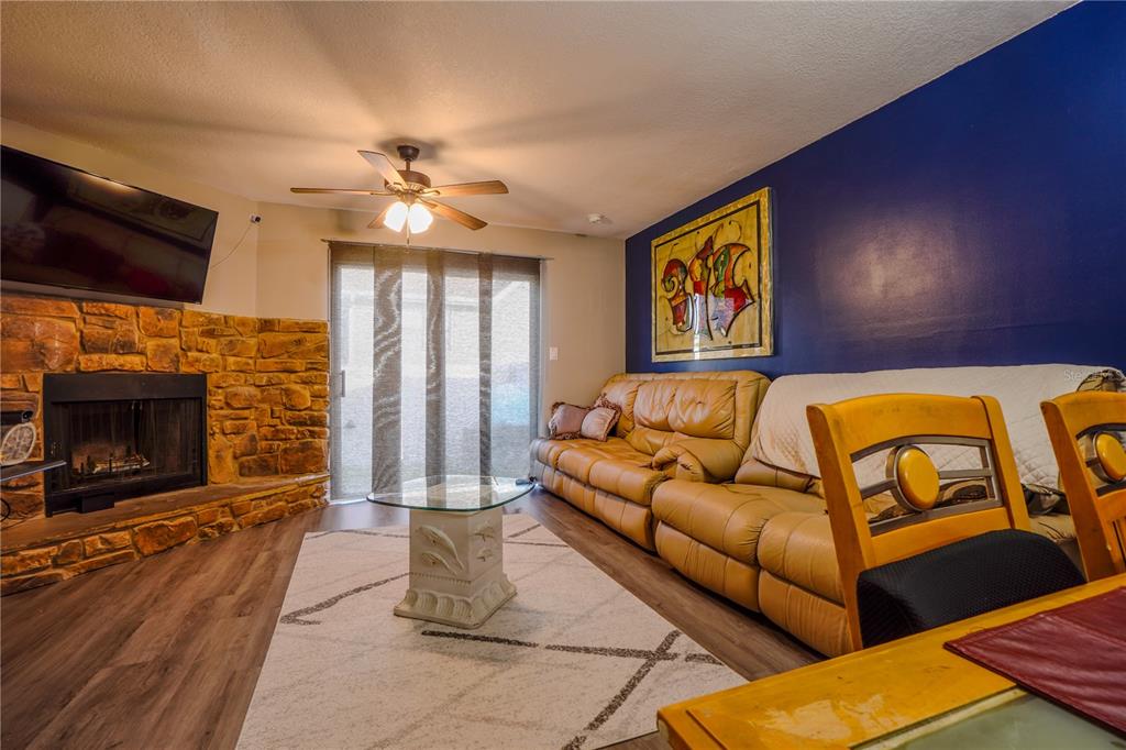 A living room features a stone fireplace, a tan leather sofa, and a dark blue wall — 104 HIDDEN ARBOR COURT, SANFORD, FL