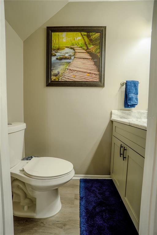 A small bathroom features a white toilet, a light-colored vanity, and a nature-themed wall art — 104 HIDDEN ARBOR COURT, SANFORD, FL