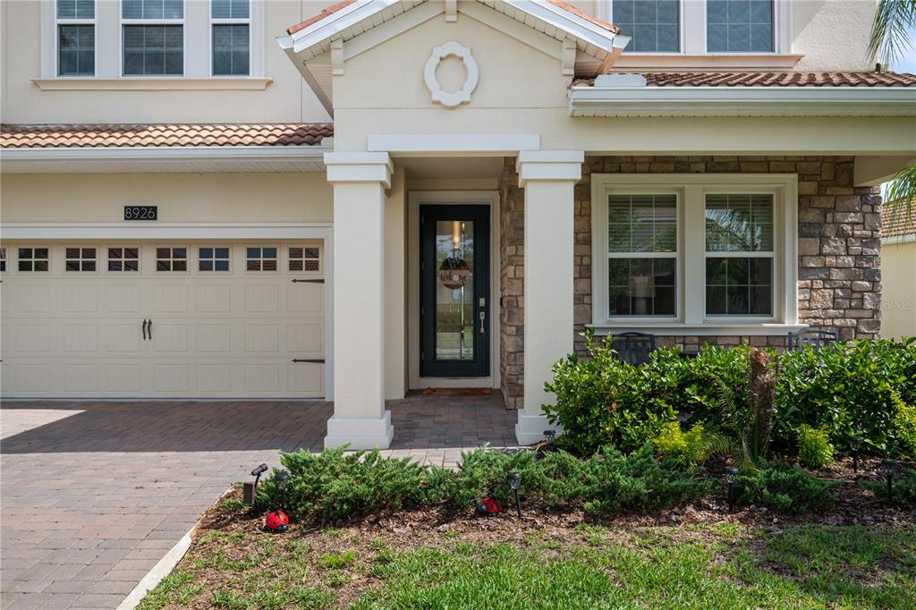 The exterior of a two-story house features a stone facade, a garage, and a porch — 8926 FALLEN OAK DRIVE, DAVENPORT, FL