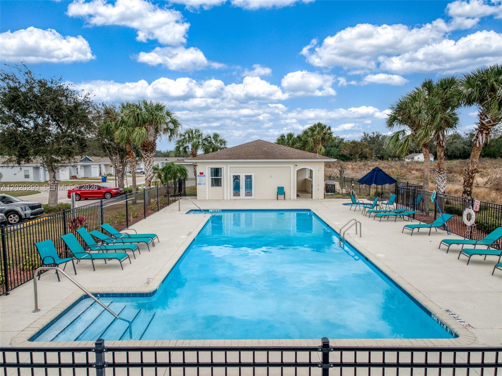 An outdoor swimming pool with lounge chairs and a clubhouse under a blue sky — 1407 Las Villas Blvd # 1407, Sebring FL 33870, SEBRING, FL