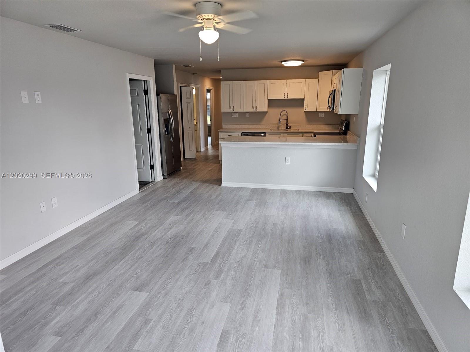An open-concept kitchen with white cabinets and a breakfast bar overlooks a living area — 1407 Las Villas Blvd # 1407, Sebring FL 33870, SEBRING, FL