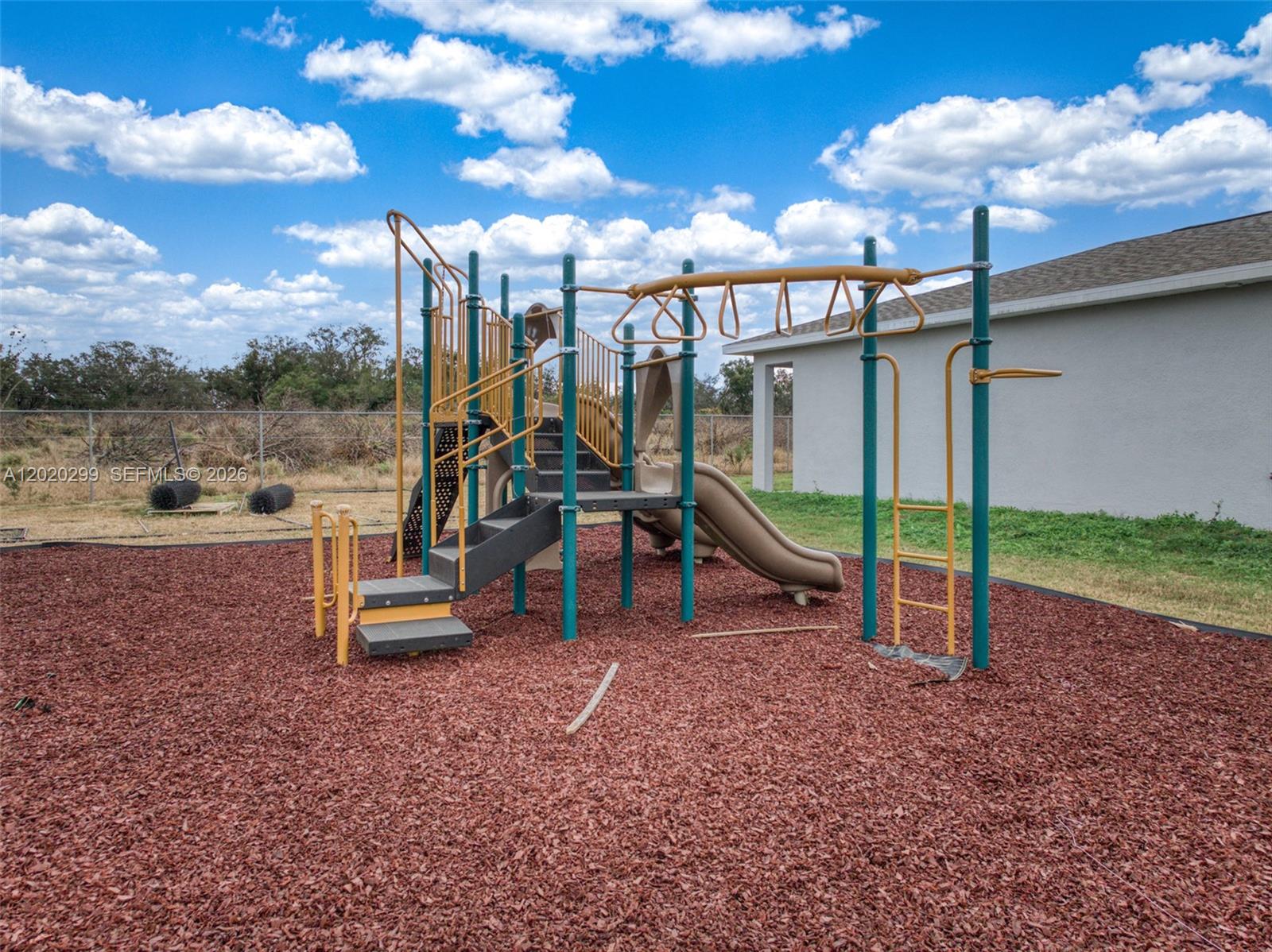 A playground structure with slides and climbing bars sits on a wood-mulched surface outdoors — 1407 Las Villas Blvd # 1407, Sebring FL 33870, SEBRING, FL