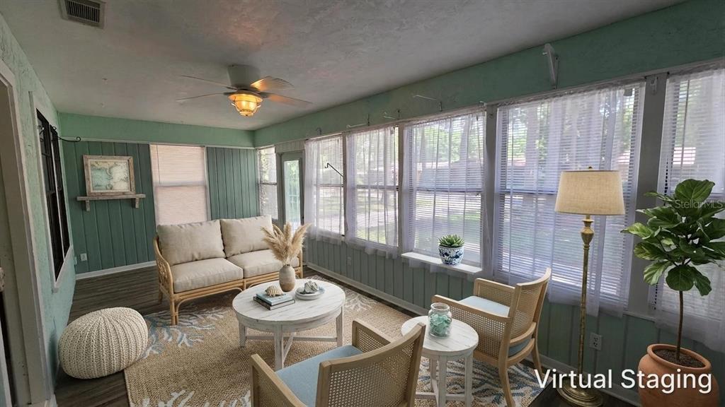 A sunroom features light green paneled walls, a ceiling fan, and virtual staging furniture — 8496 NW 38TH TERRACE, GAINESVILLE, FL