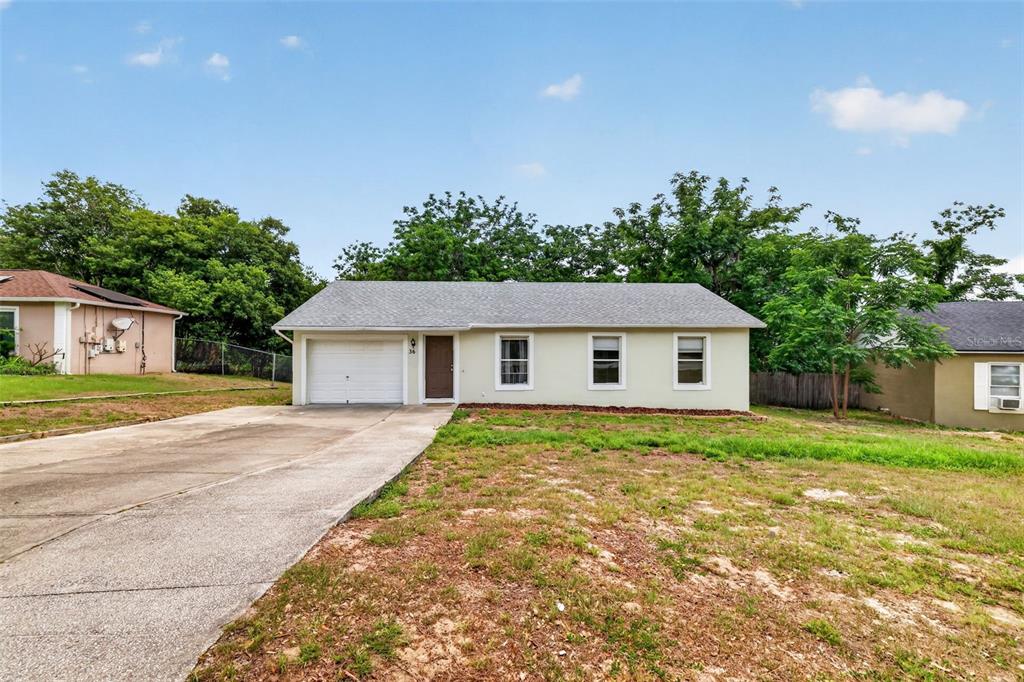 A single-story house with a light-colored exterior, a garage, and a concrete driveway — 36 BAY RIDGE LOOP, MASCOTTE, FL