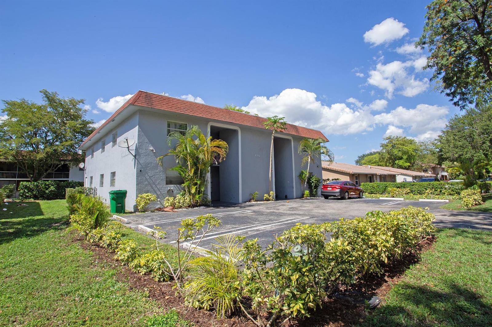A two-story apartment building with a red roof, gray exterior, and a paved parking lot — CORAL SPRINGS, FL