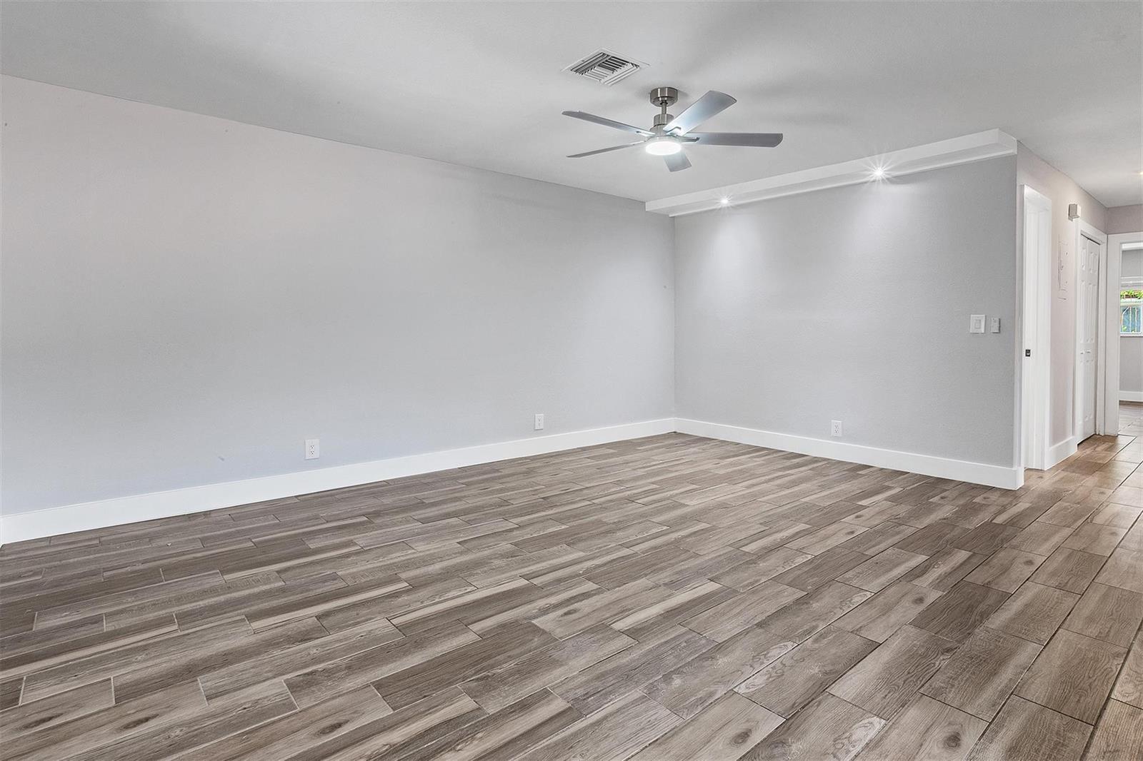 An empty room features light gray walls, wood-look tile flooring, and a ceiling fan — CORAL SPRINGS, FL
