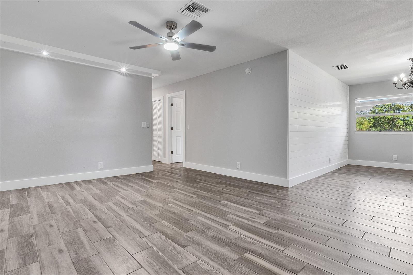 An empty room features gray wood-look tile flooring, light gray walls, and a white shiplap accent wall — CORAL SPRINGS, FL
