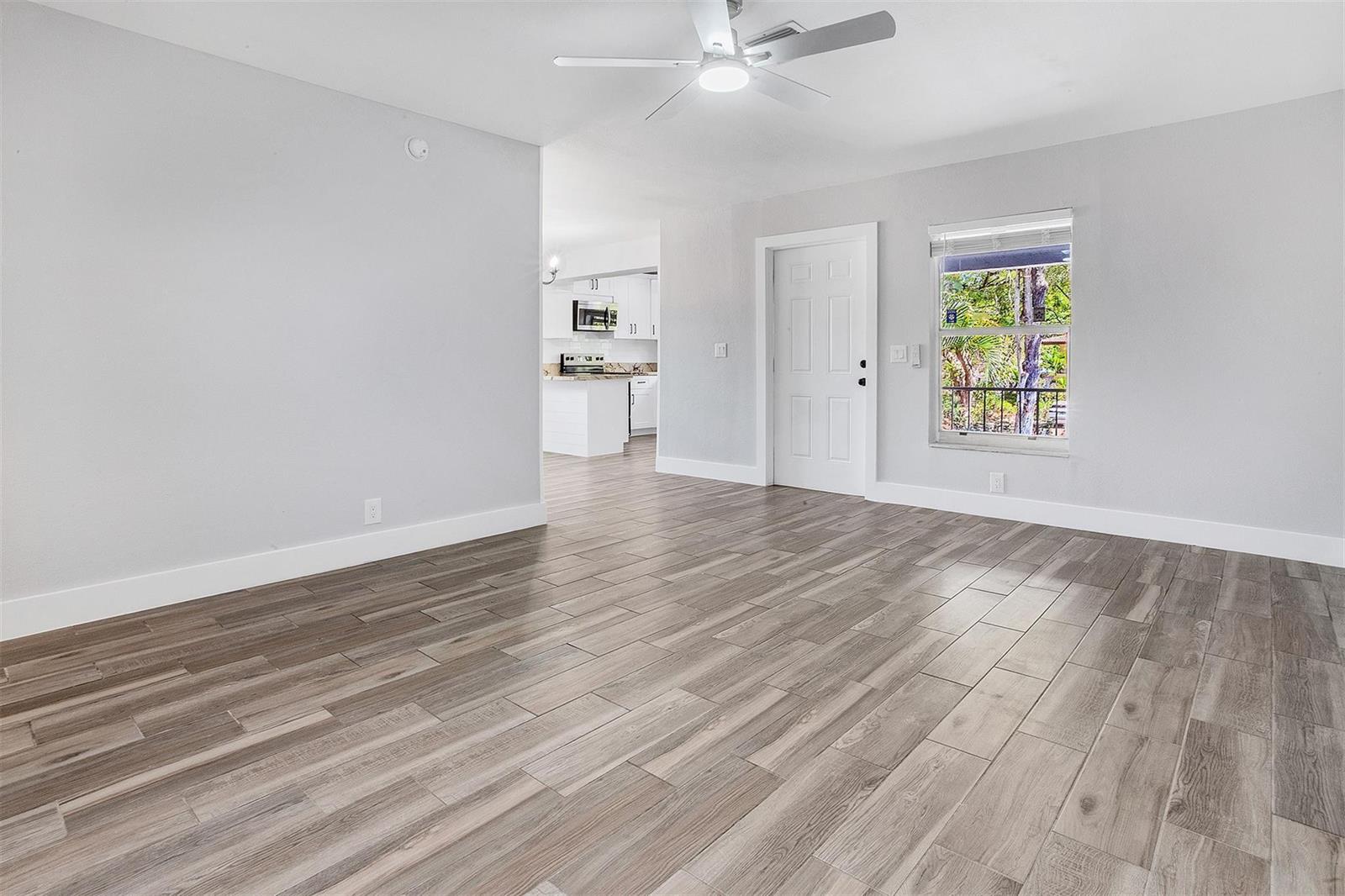 An empty room with light gray walls, wood-look tile flooring, a ceiling fan, and window — CORAL SPRINGS, FL