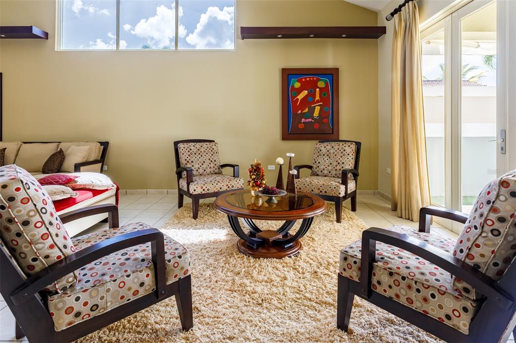 A living room features four patterned armchairs, a round coffee table, and a large window — 121 CAMINOS DE LOS LOTOS SABANERA, DORADO, PR