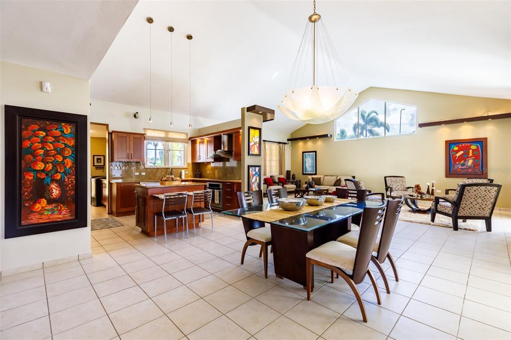 An open-concept living and dining area features a kitchen island, tile floors, and vaulted ceilings — 121 CAMINOS DE LOS LOTOS SABANERA, DORADO, PR