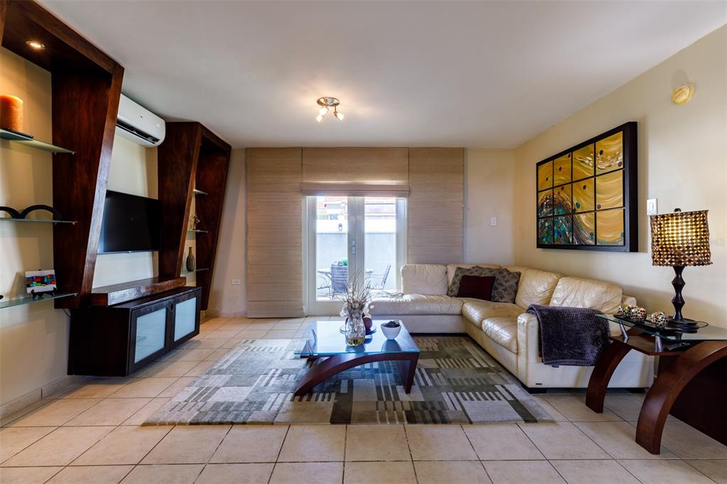 A living room features a white sectional sofa, a glass coffee table, and wood shelving — 121 CAMINOS DE LOS LOTOS SABANERA, DORADO, PR