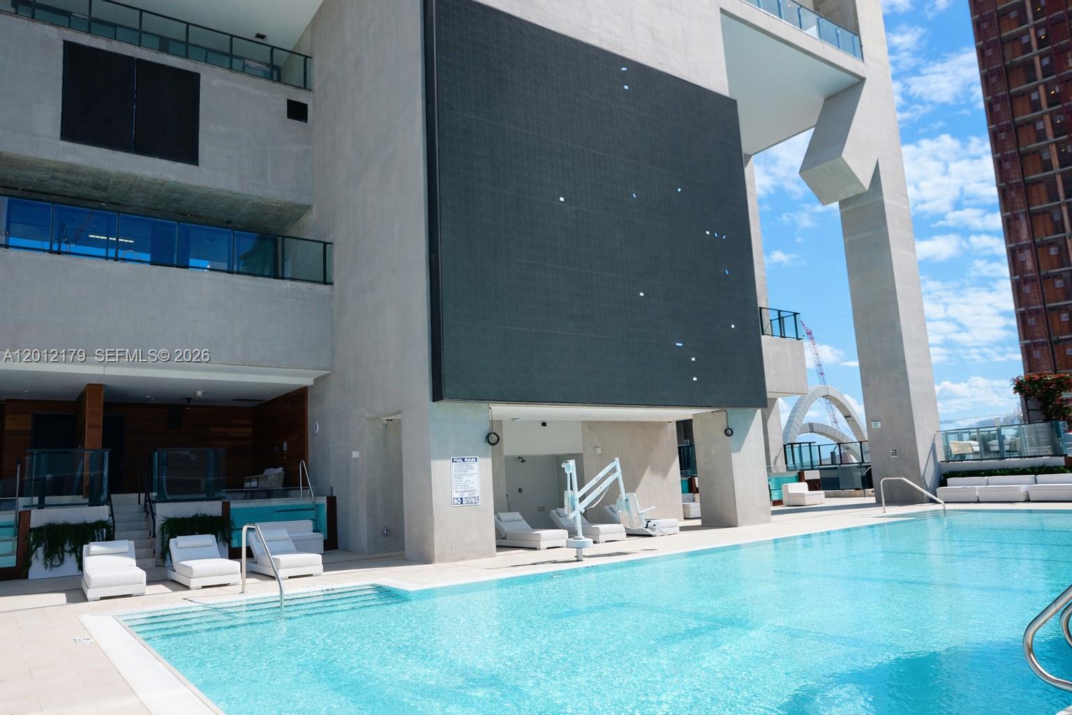 A swimming pool sits on a terrace beneath a large screen mounted on a building — 20 NE 11 th st # 3403A, Miami FL 33132, MIAMI, FL