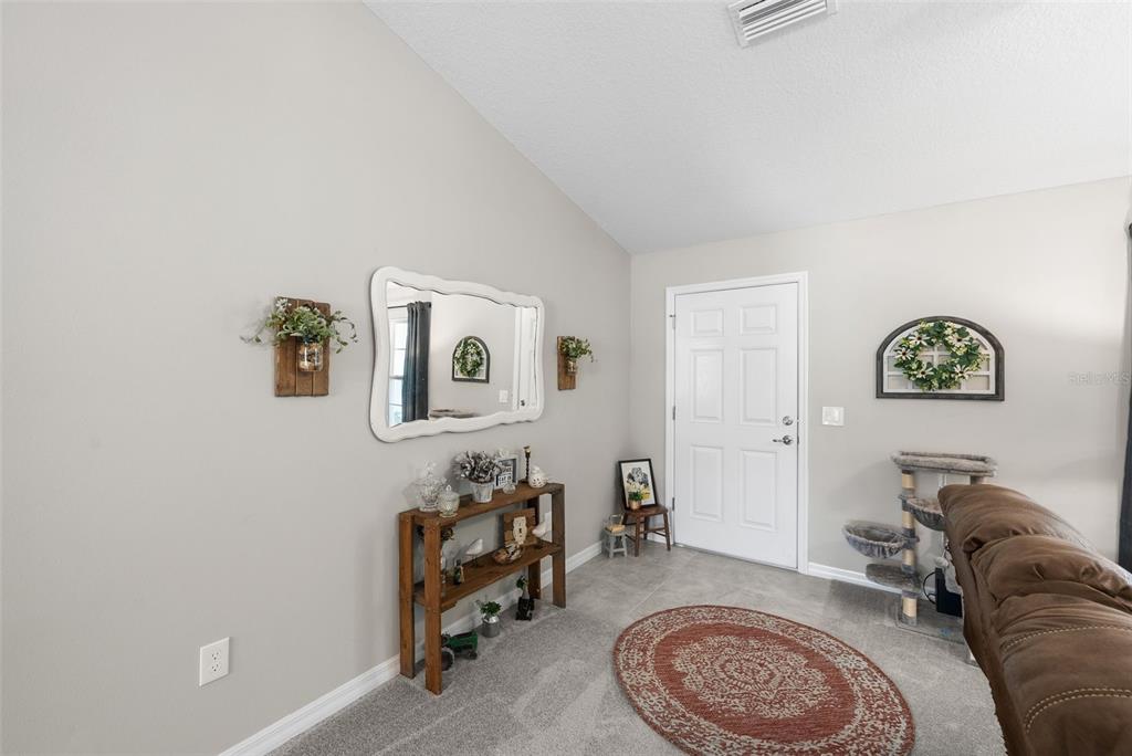 A living room features a front door, a console table, a mirror, and a cat tree — 1831 NE 160TH PLACE, CITRA, FL