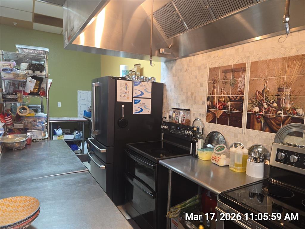A commercial kitchen features stainless steel countertops, a black refrigerator, and a range hood — 0000 BRANDON BOULEVARD, BRANDON, FL
