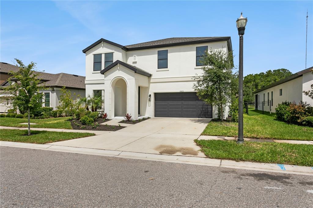 A two-story white house with a dark garage door and an arched entryway — 12633 SHETLAND WALK DRIVE, LITHIA, FL