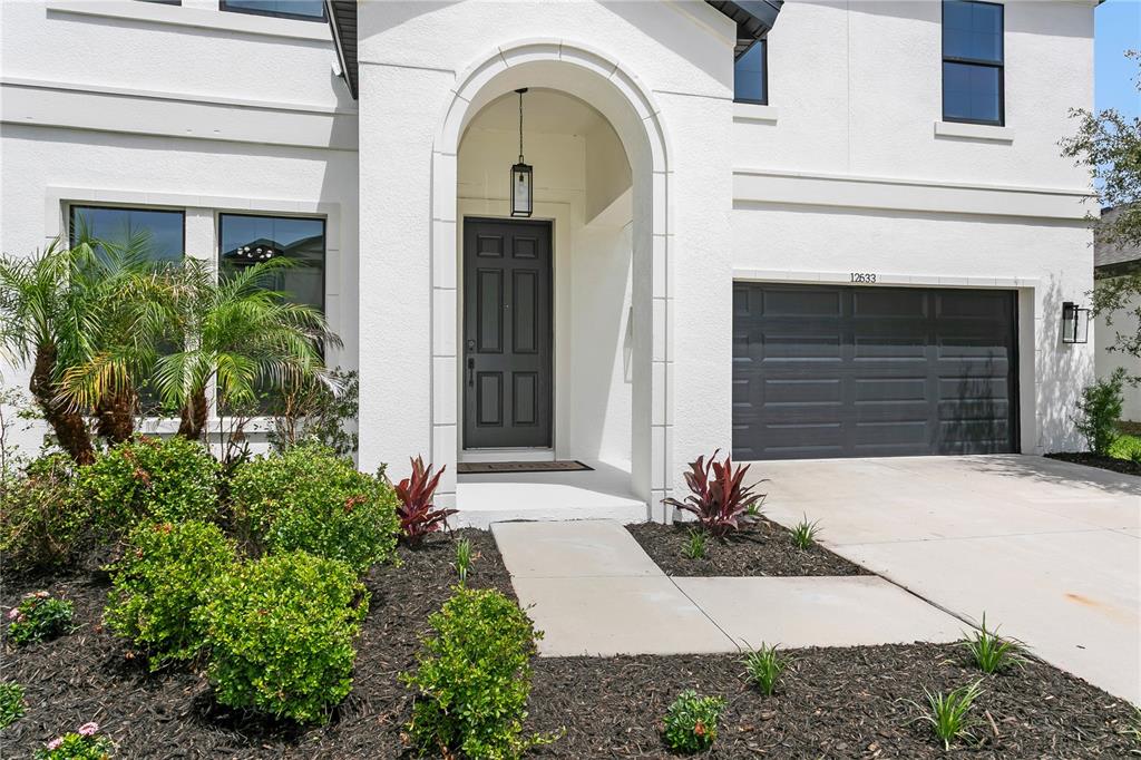 A white two-story house features a dark front door, arched entryway, and attached garage — 12633 SHETLAND WALK DRIVE, LITHIA, FL