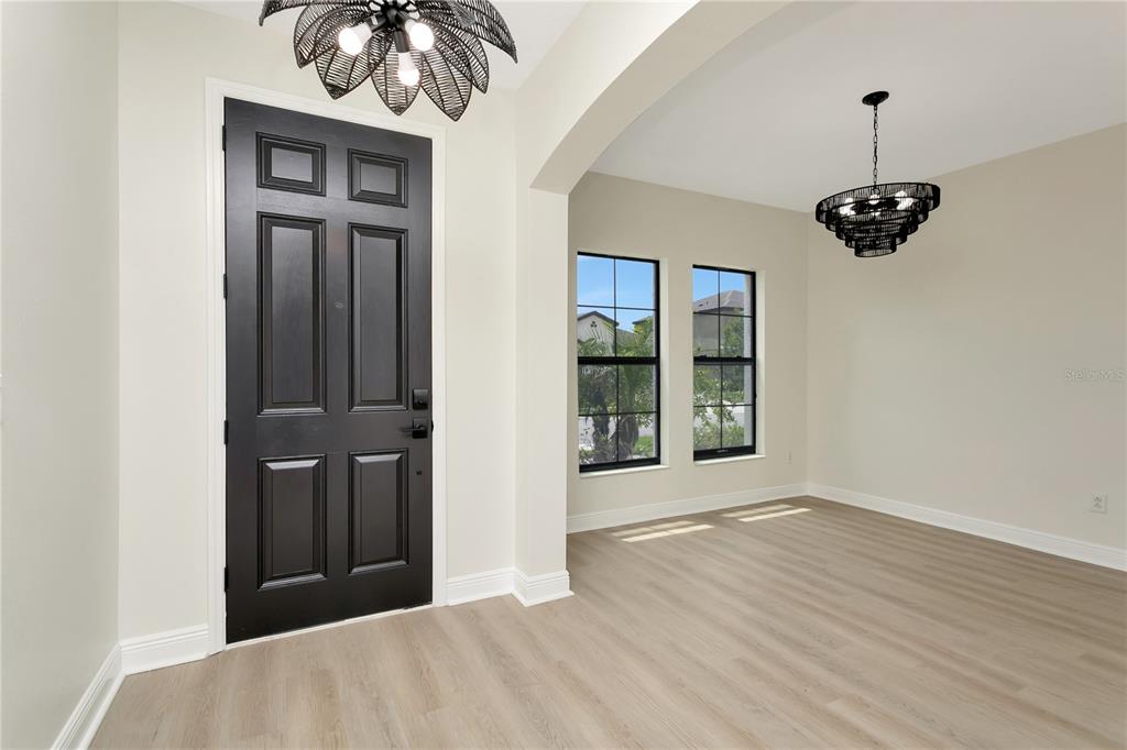 An entryway with a black door and light wood flooring leads into a dining area — 12633 SHETLAND WALK DRIVE, LITHIA, FL