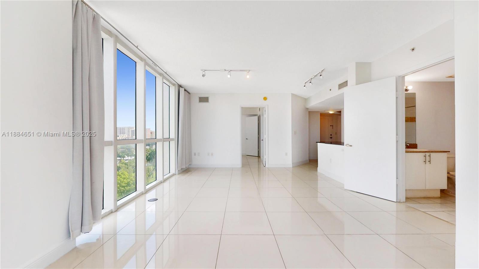 An empty room with white tile floors, large windows, and an adjacent bathroom — 1871 NW S River Dr # 1205, Miami FL 33125, MIAMI, FL