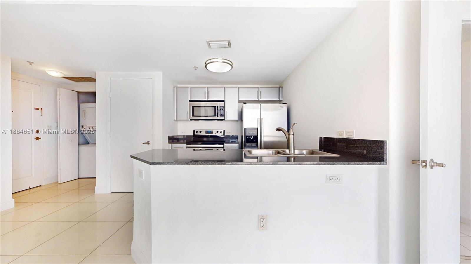 A kitchen features stainless steel appliances, dark granite countertops, and white cabinetry — 1871 NW S River Dr # 1205, Miami FL 33125, MIAMI, FL