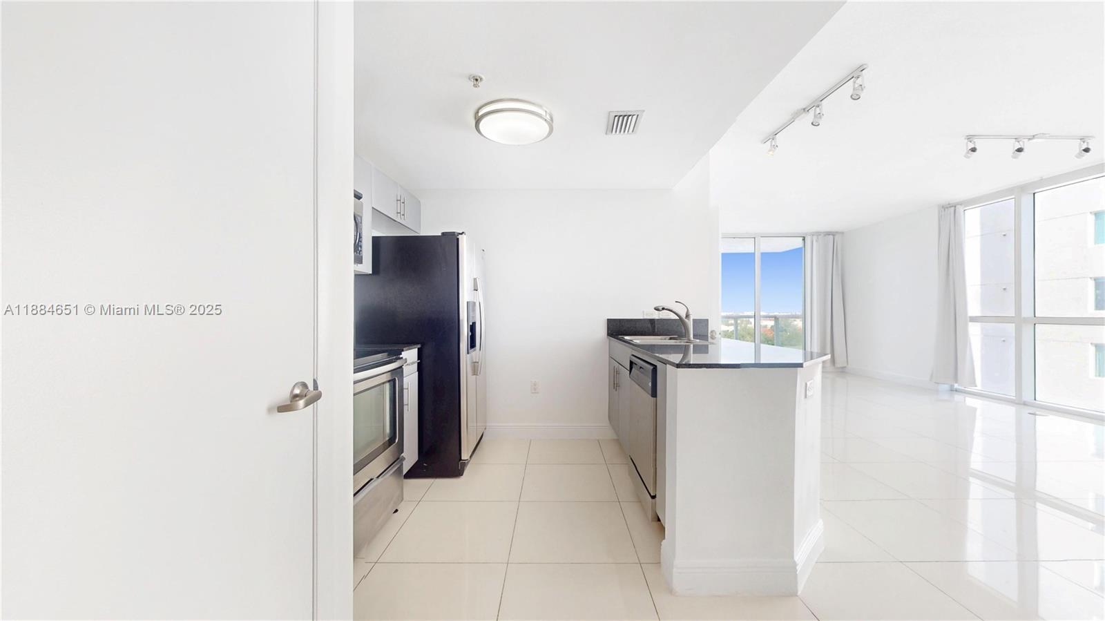 A kitchen with stainless steel appliances and a breakfast bar opens into a bright living area — 1871 NW S River Dr # 1205, Miami FL 33125, MIAMI, FL