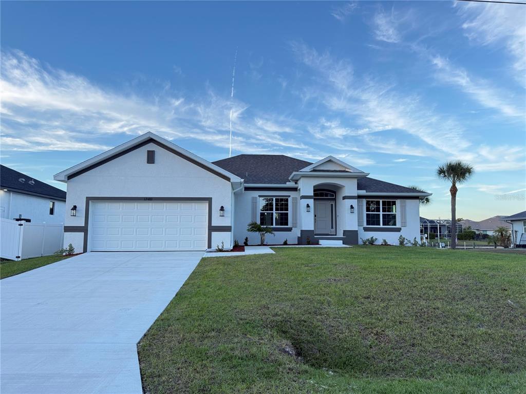 A single-story house with a white stucco exterior, a two-car garage, and a front porch — 12482 KNEELAND TERRACE, PORT CHARLOTTE, FL