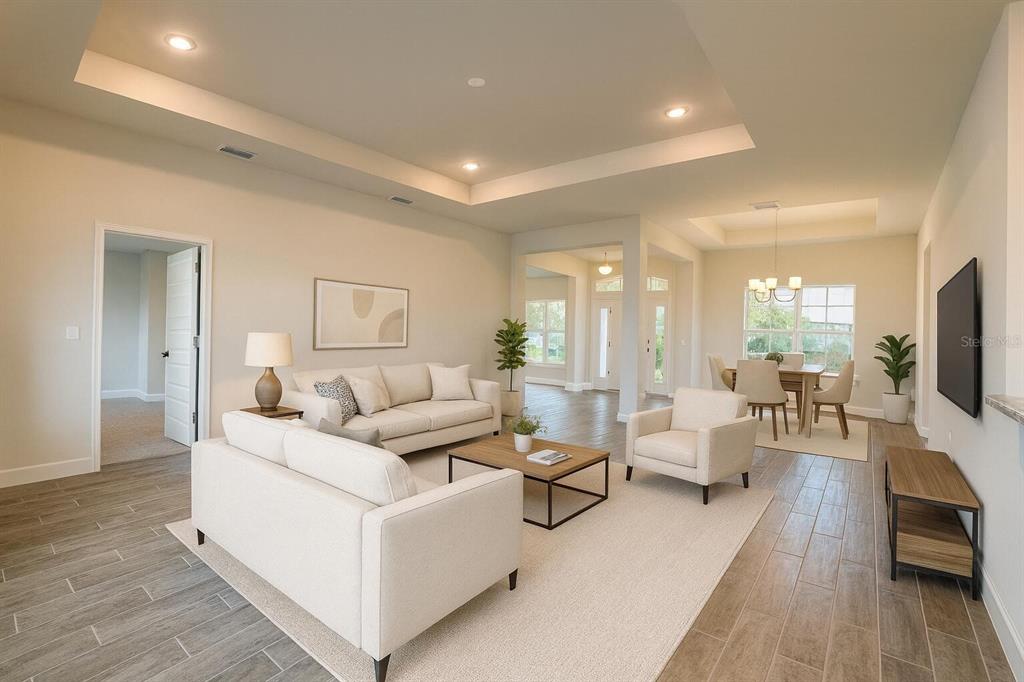 An open-concept living and dining area features light-colored furniture, tile flooring, and tray ceilings — 12482 KNEELAND TERRACE, PORT CHARLOTTE, FL